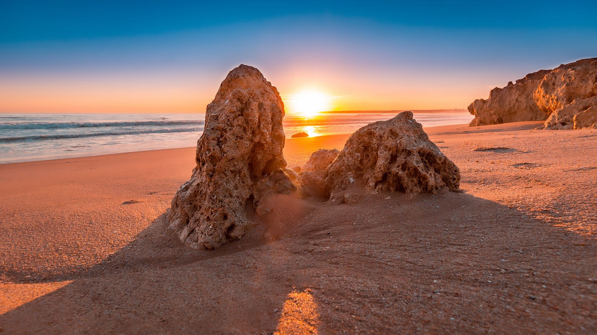 Algarve winter sunset with sun setting between two rocks on the beach